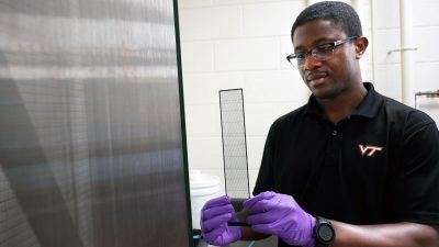 Jimmy Kaindu inspects a new collecting prototype beside the original fog harp. Photo by Alex Parrish for Virginia Tech.
